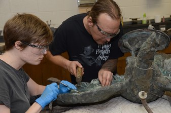 Conservators remove old patches from artifact