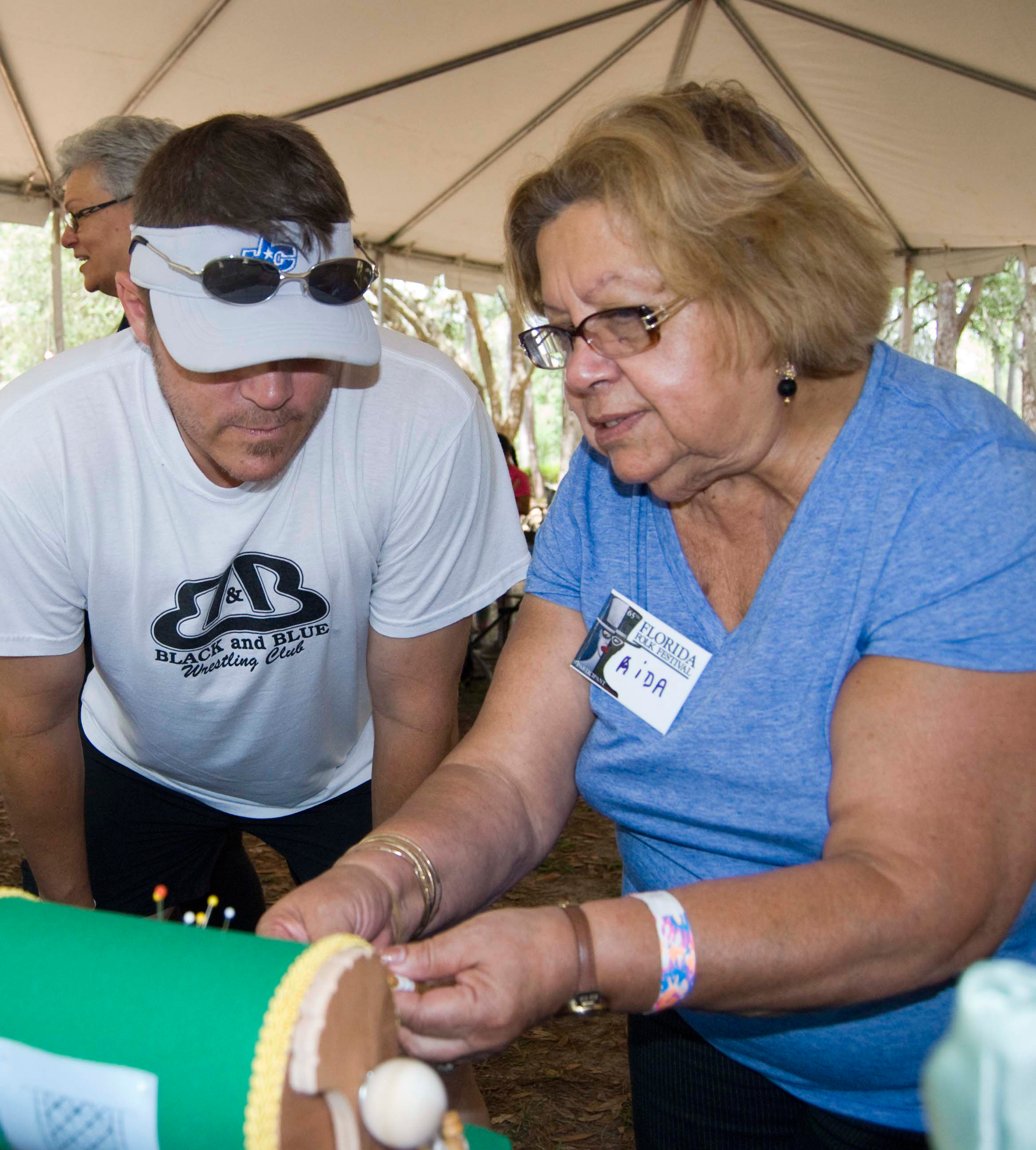 Photo of Aida Rodriguez demonstrating her art to a visitor at the Florida Folk Festival
